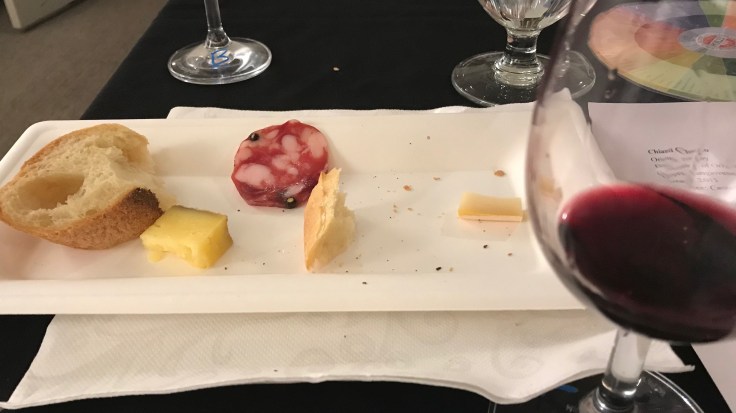 Partly eaten bread and cheese on a plate with a glass of red wine