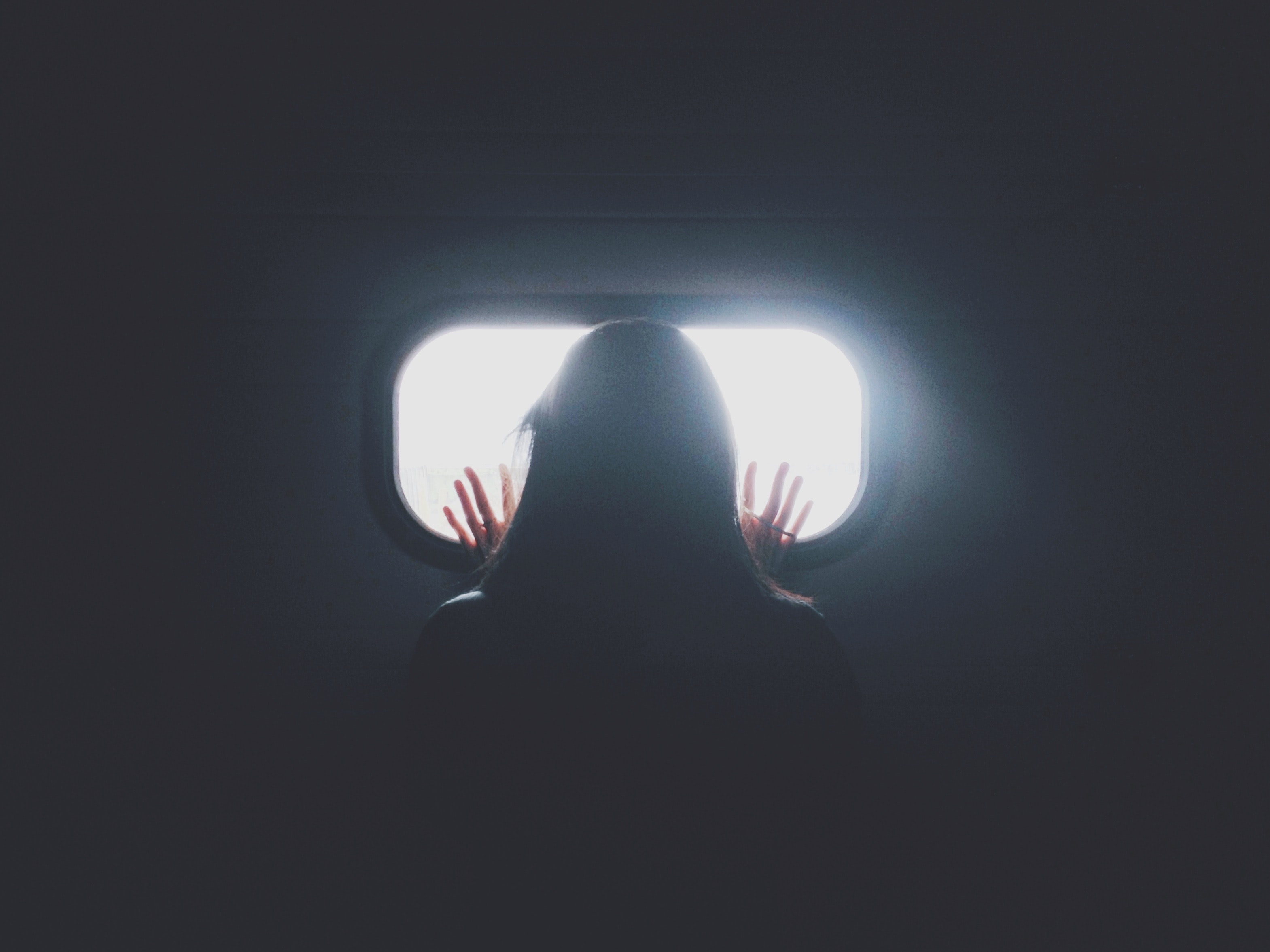 Woman holding hands up against a window 